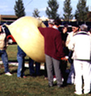 Inflating a weather balloon.  No, he's not blowing that up with his lips.  They use helium these days, not hot air!